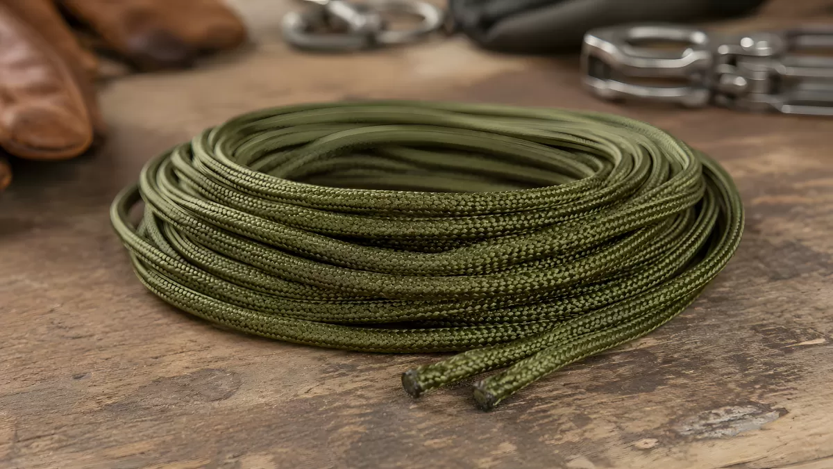 Olivgrüne Paracord-Schnur aufgerollt auf Holztisch
