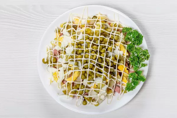 Olivier salad on a white wooden background. The view from the top (Flip 2019)