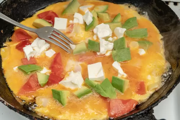 Omelet with Avocado Cheese and Tomatoes in the frying pan (Flip 2019)
