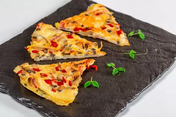Omelette with vegetables and micro greens on a black stone tray