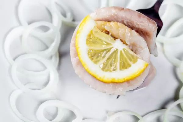 On the fork wearing a roll of herring fillet on a white plate