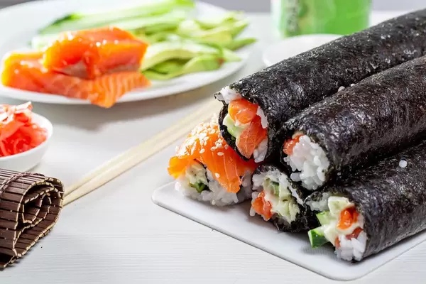 On white table, the ingredients for sushi and ready rolls on the kitchen Board