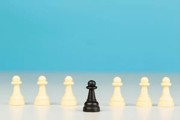 One black pawn in front and many white ones behind, business concept