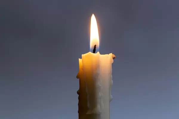 One burning candle on a dark background