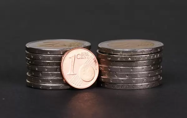 One Euro cent coin placed in front of piles of coins