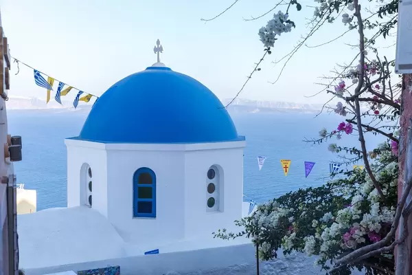 One of the famous blue domes in the picturesque village of Oia in Santorini with sea in the background