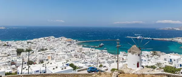 One of the landmark windmills of Mykonos and view of the city and port of Chora. Panoramic image