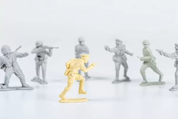 One yellow plastic toy soldier and many gray toy soldiers. Unequal power concept