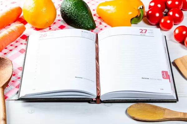 Open book with vegetables and wooden spoons
