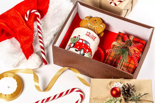 Open christmas gift box with cup, gingerbread and present