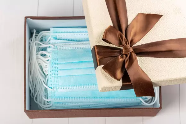 Open gift box with many medical masks inside, top view