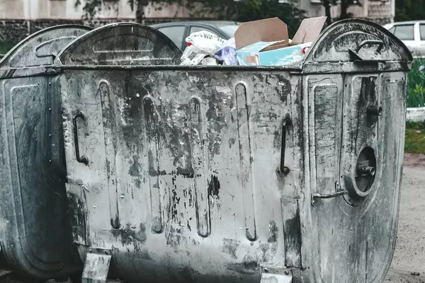Open iron garbage container with garbage inside