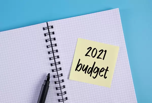 Open notebook and yellow sticky note with 2021 Budget text