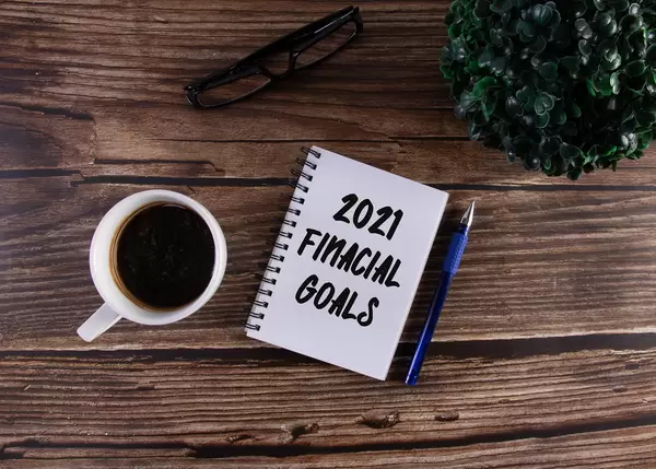 Open notebook with 2021 Financial Goals text on wooden table