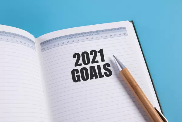 Open notebook with 2021 Goals text and pen on blue background