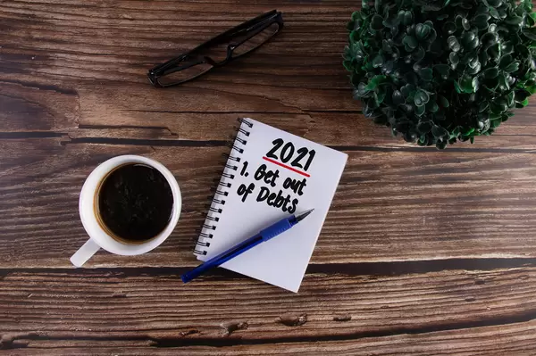 Open notebook with Get out of Debts goal on wooden table