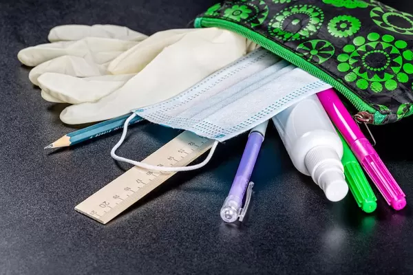Open pencil case with school supplies and personal protection items. Study during quarantine