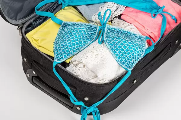 Open suitcase with beach or summer clothes