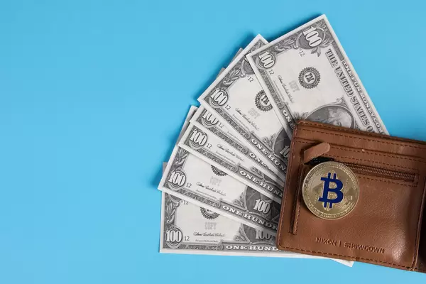 Open wallet with dollar banknotes and golden Bitcoin coin