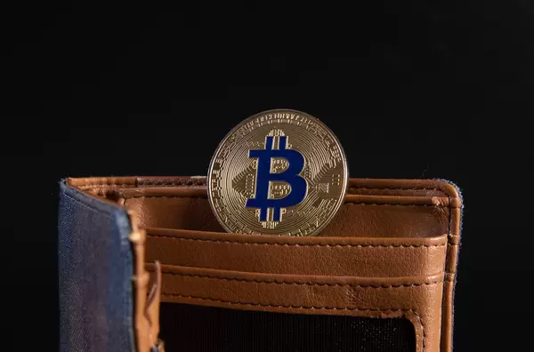 Open wallet with golden Bitcoin coin on black background