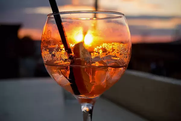 Orange Abenddämmerung hinter einem alkoholischen Drink im Longdrinkglas