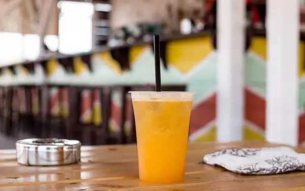 Orange drink in plastic cups with ice on the beach.