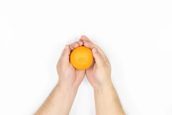 Orange in the hand isolated above white background with copy space