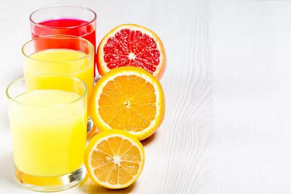 Orange, lemon and grapefruit fresh juices on a white wooden background (Flip 2019)