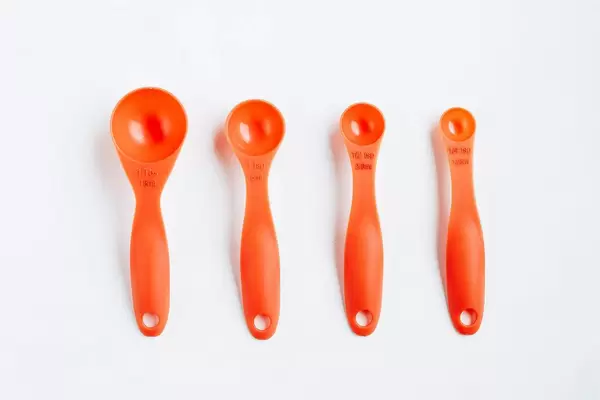 Orange plastic measuring spoons on white background.