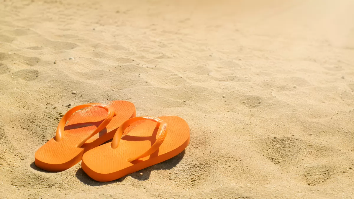 Orangefarbene Flip-Flops im Sand am Strand