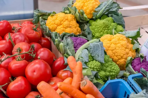 Oranger und violetter Blumenkohl, Romanesco, Karotten Schalotten und Tomaten am Timeout Market in Lissabon