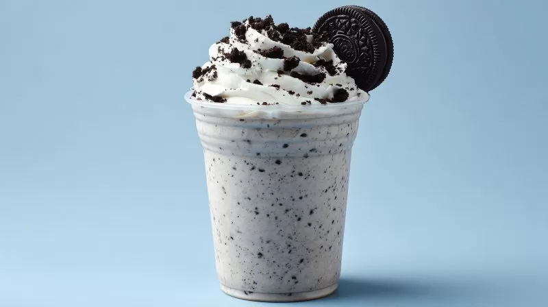 Oreo-Milchshake mit Sahne und Keks auf blauem Hintergrund