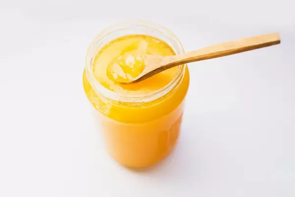 Organic honey in a jar with wooden spoon on white background. Top view.