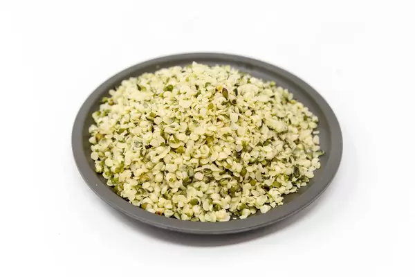 Organic vegan peeled hemp seeds on a black plate