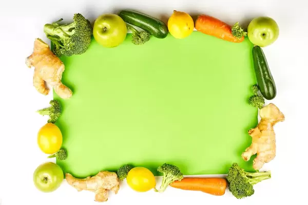 Organic vegetables and fruits frame on green background with copy space