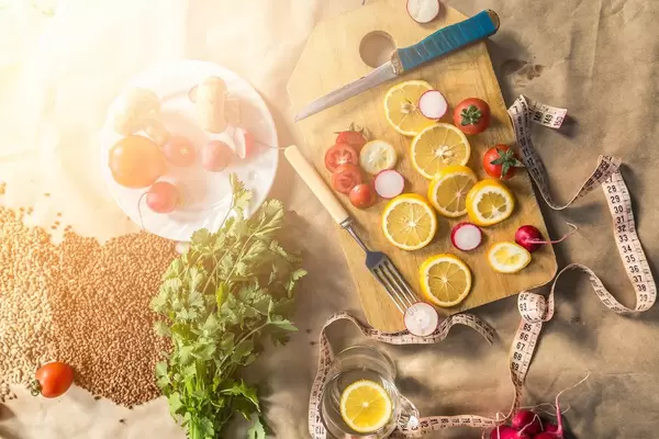 Organisches, vegetarisches Bio-Essen mit Schneidebrett, Maßband, Kräutern und Zitronenscheiben