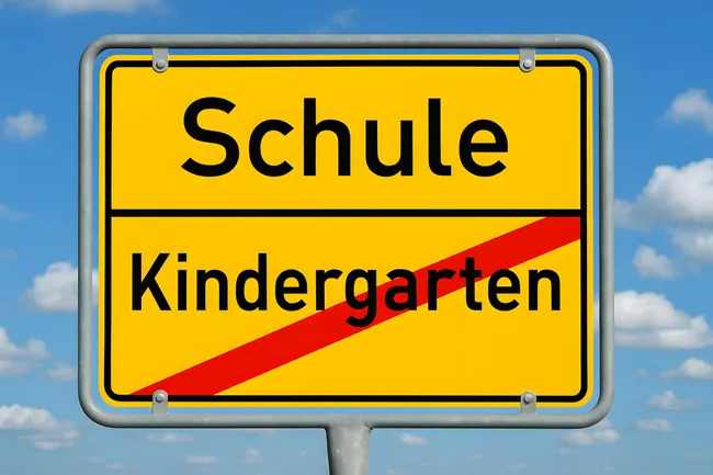 Ortsschild mit Aufschrift 'Schule' und 'Kindergarten'