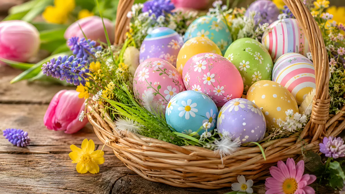 Osterkorb mit bunten bemalten Eiern und Frühlingsblumen