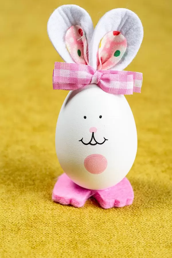 Ostern-Deko: Ei als Osterhase gebastelt vor gelbem Hintergrund