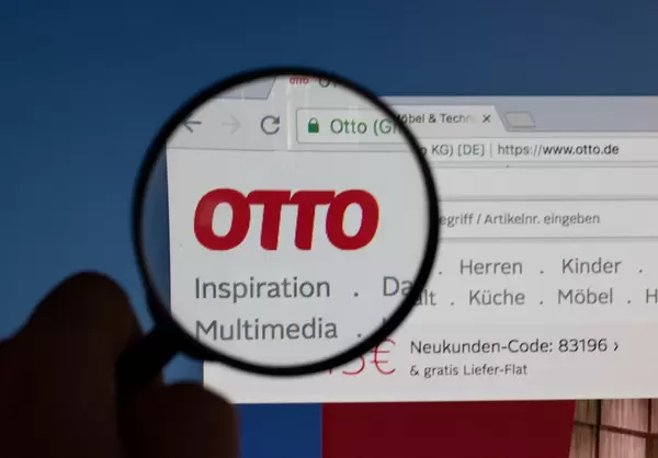 Otto-Logo am PC-Monitor, durch eine Lupe fotografiert