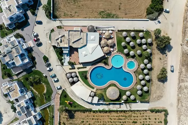 Overhead Drohnenaufnahme: Villa mit Schwimmbad und runden Sonnenschirmen auf Naxos, Zykladen