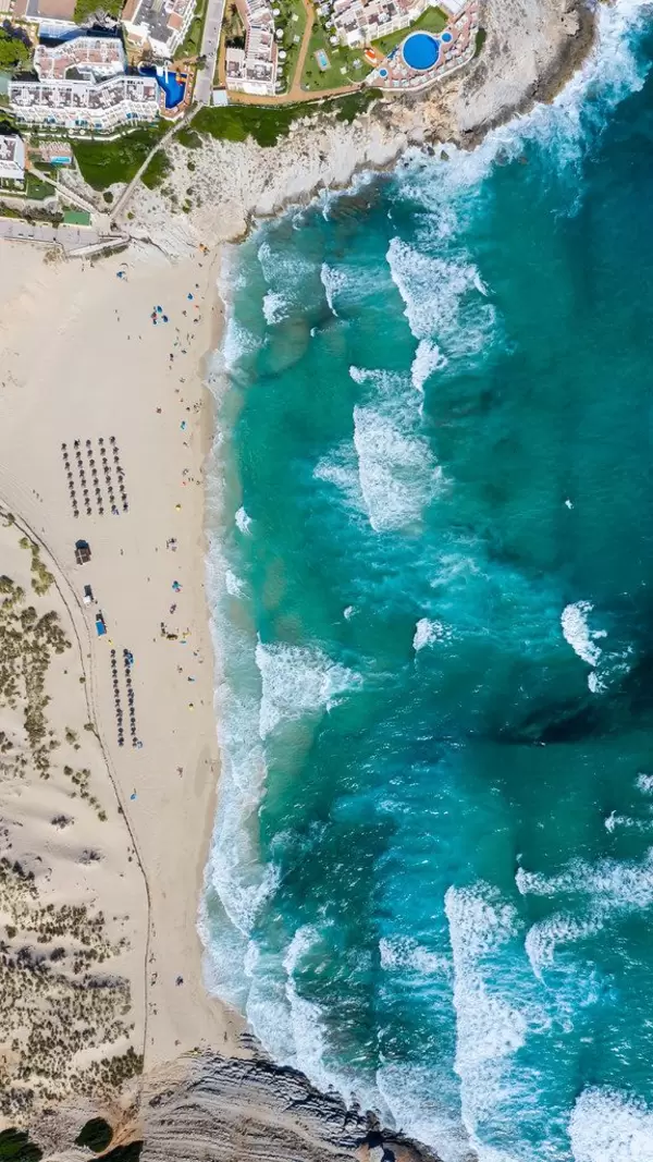 Overhead-Luftaufnahme vom langen Strand und Bucht von Cala Mesquida mit Wellen und Dünen