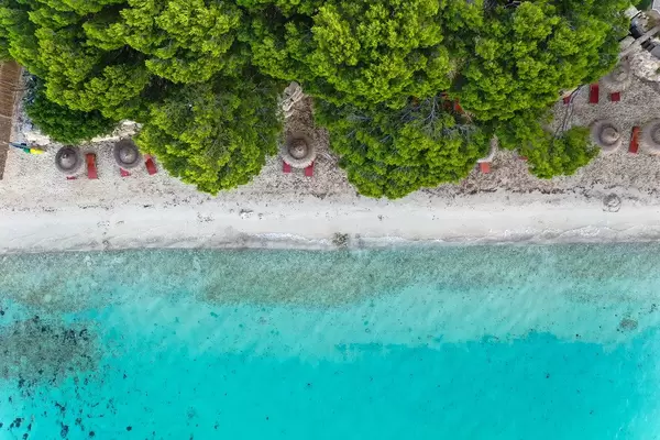 Overhead shot: Playa de Formentor on Mallorca with reddish-brown sun beds and straw parasols