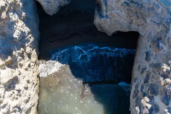 Overhead shot: the waves break as they reach the small beach hidden by the rock faces in Papafrangas