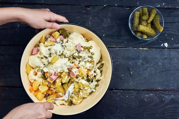 Overhead view of a woman mixing Olivier salad ingredients