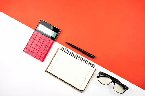 Overhead view of calculator, notepad and eyeglasses