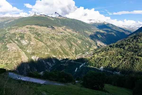 Overlook of a Swiss Valley with a village down below and road passing through stone sharp walls
