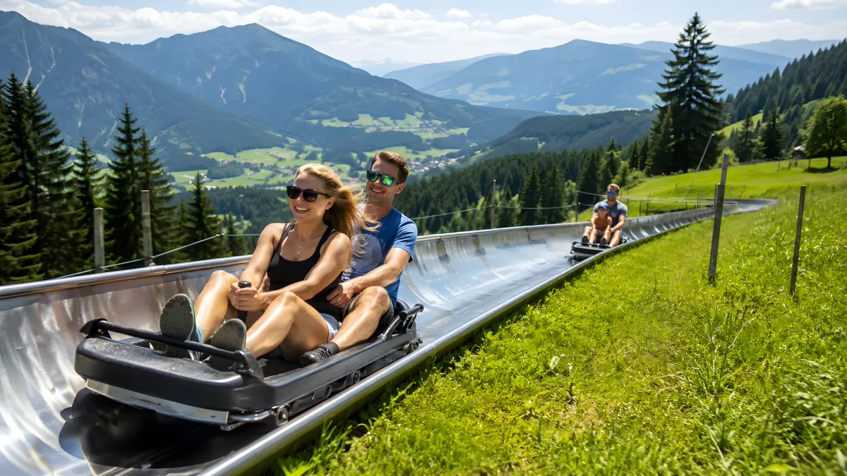Paar fährt Sommerrodelbahn in den Alpen bergab