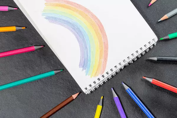 Painted rainbow in a notebook and a variety of colored pencils on a black background (Flip 2019)
