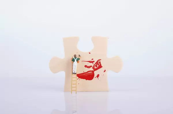 Painter on ladder painting a puzzle piece